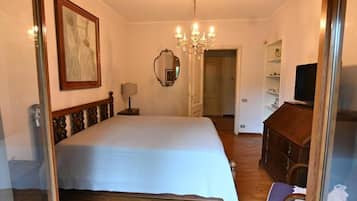 Une chambre à coucher avec un lit, un lustre, une commode et un téléviseur.