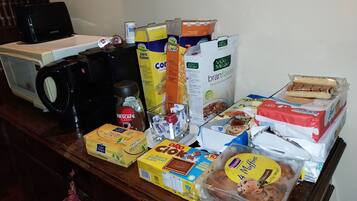 A variety of food items and a coffee machine on a wooden surface.