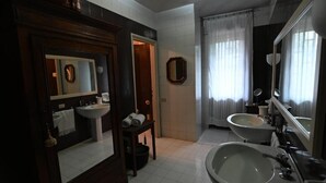 Ein Badezimmer mit zwei Waschbecken, einem Spiegel und einer Tür zu einem anderen Raum.