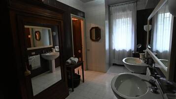 Une salle de bain avec deux lavabos, un miroir et une porte donnant sur une autre pièce.