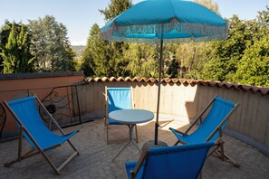 An outdoor patio with two blue lounge chairs, a small round table, and a blue umbrella. - Villa Francesca B&B (Grumello del Monte)