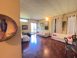 A spacious living room with a wooden floor, white sofas, and a dining area with chairs. - Villa Francesca B&B (Grumello del Monte)