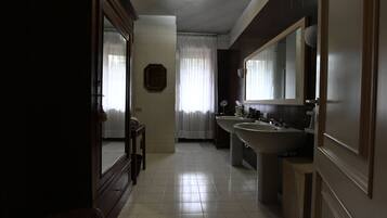A bathroom with a large mirror, two sinks, and a window with curtains.