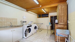 A laundry room with two front-loading washing machines, a drying rack, and a small table with a towel. - Gîte Gretel with Shared Terrace, Garden, and Wi-Fi (Bossendorf)