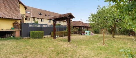 A residential area with a house, a covered outdoor seating area, and a small play structure.