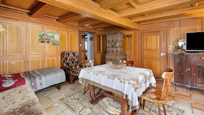 A traditional wooden interior with a dining table, chairs, a sofa, and a television on a cabinet. - Gîte Gretel with Shared Terrace, Garden, and Wi-Fi (Bossendorf)