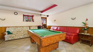 A pool table in a room with a sofa and a red chair.