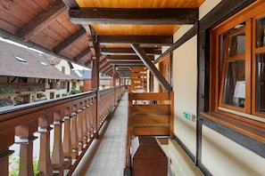 A corridor with wooden beams and a balcony with a railing.