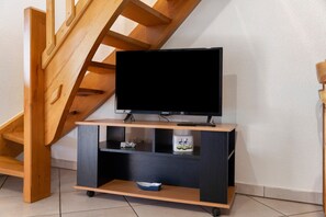 Un moble d'entreteniment de fusta amb un televisor de pantalla plana, una petita estant i un bol.