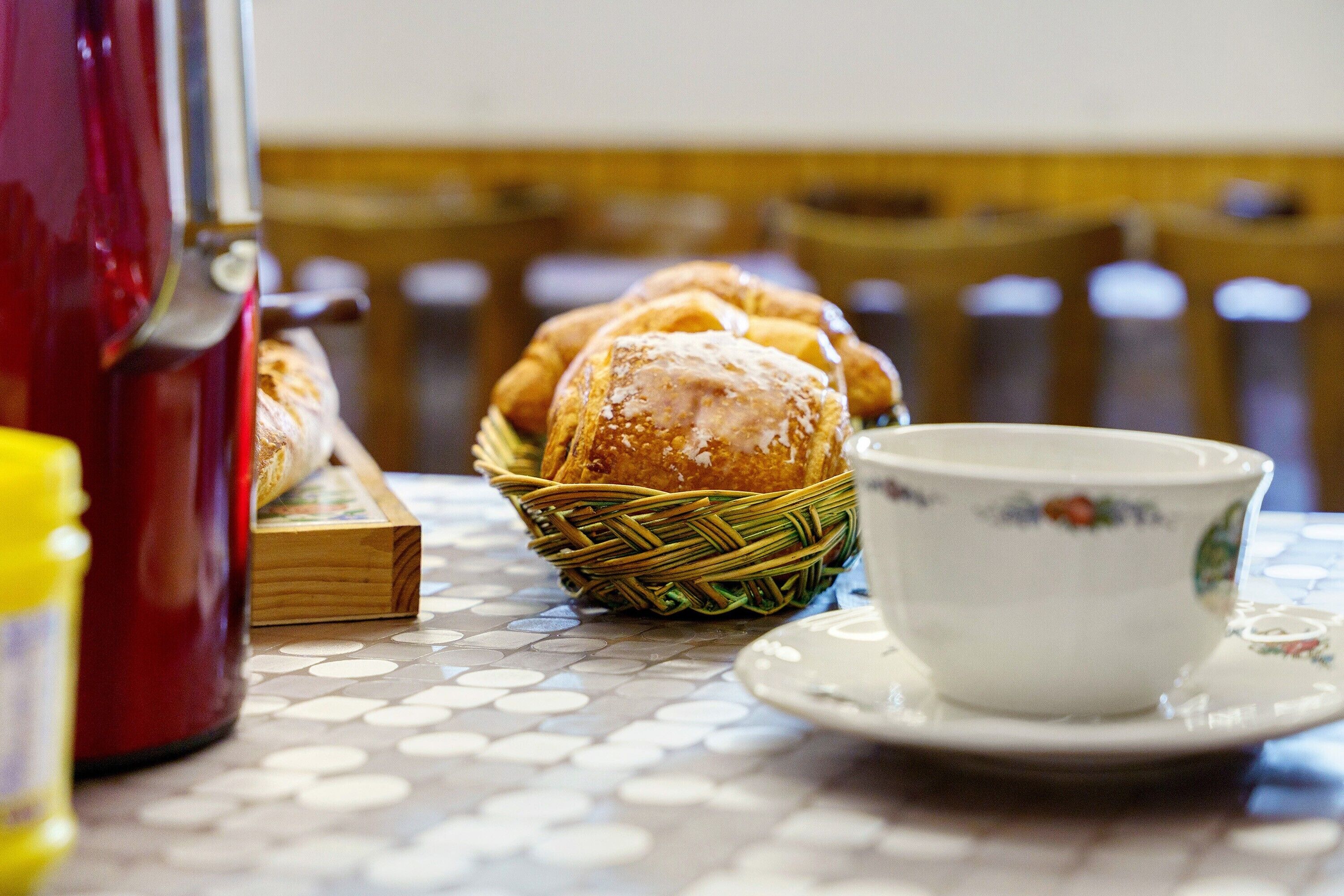 A table with a basket of pastries and a cup of tea.