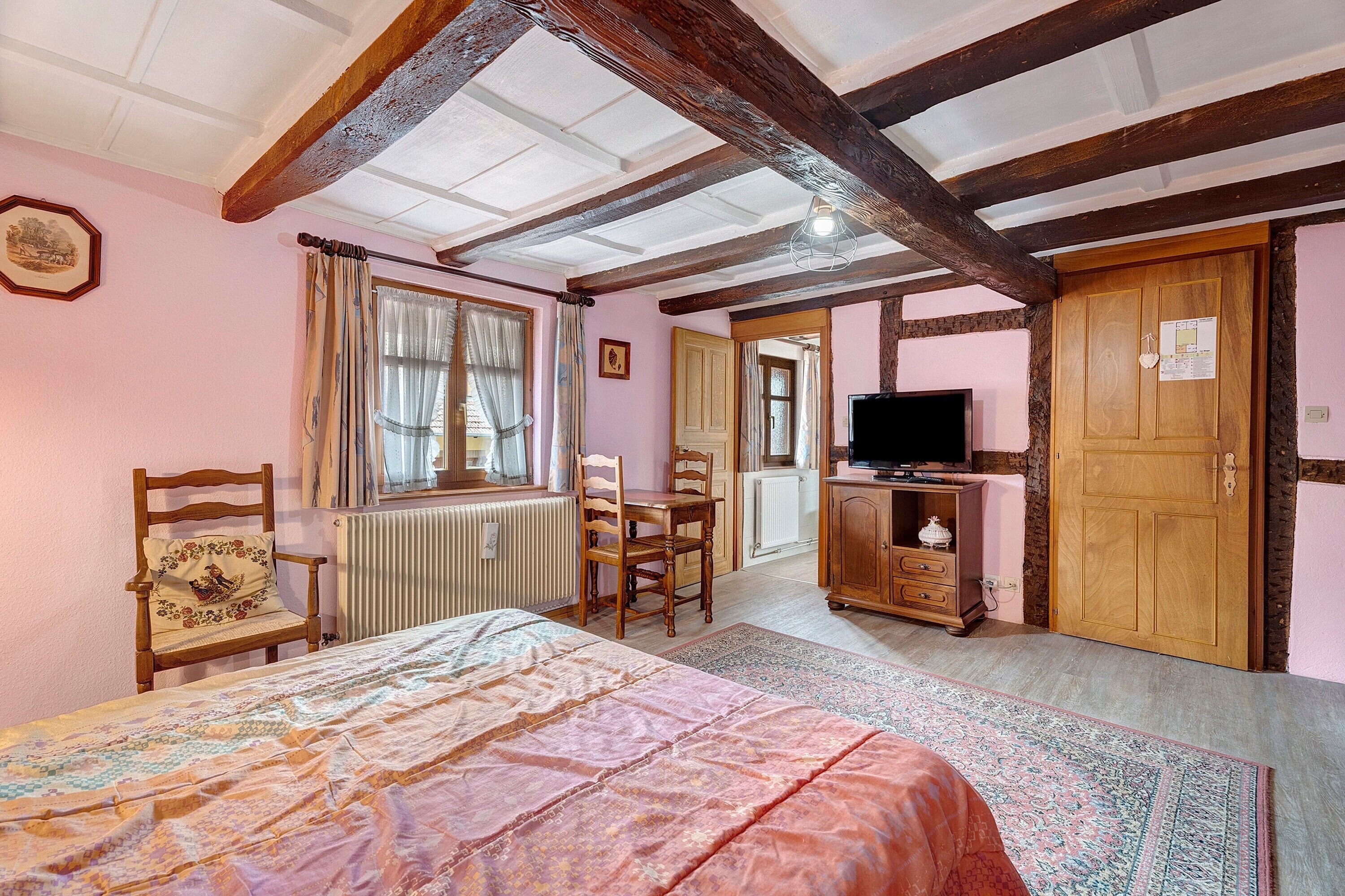 Een slaapkamer met een bed, een stoel, een televisie en een deur.