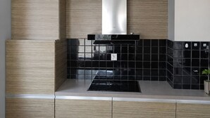Una cocina moderna con estufa negra, armarios blancos y salpicadero negro.