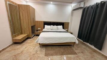A bedroom with a bed, nightstands, a wooden wardrobe, a ceiling fan, and a window with curtains.