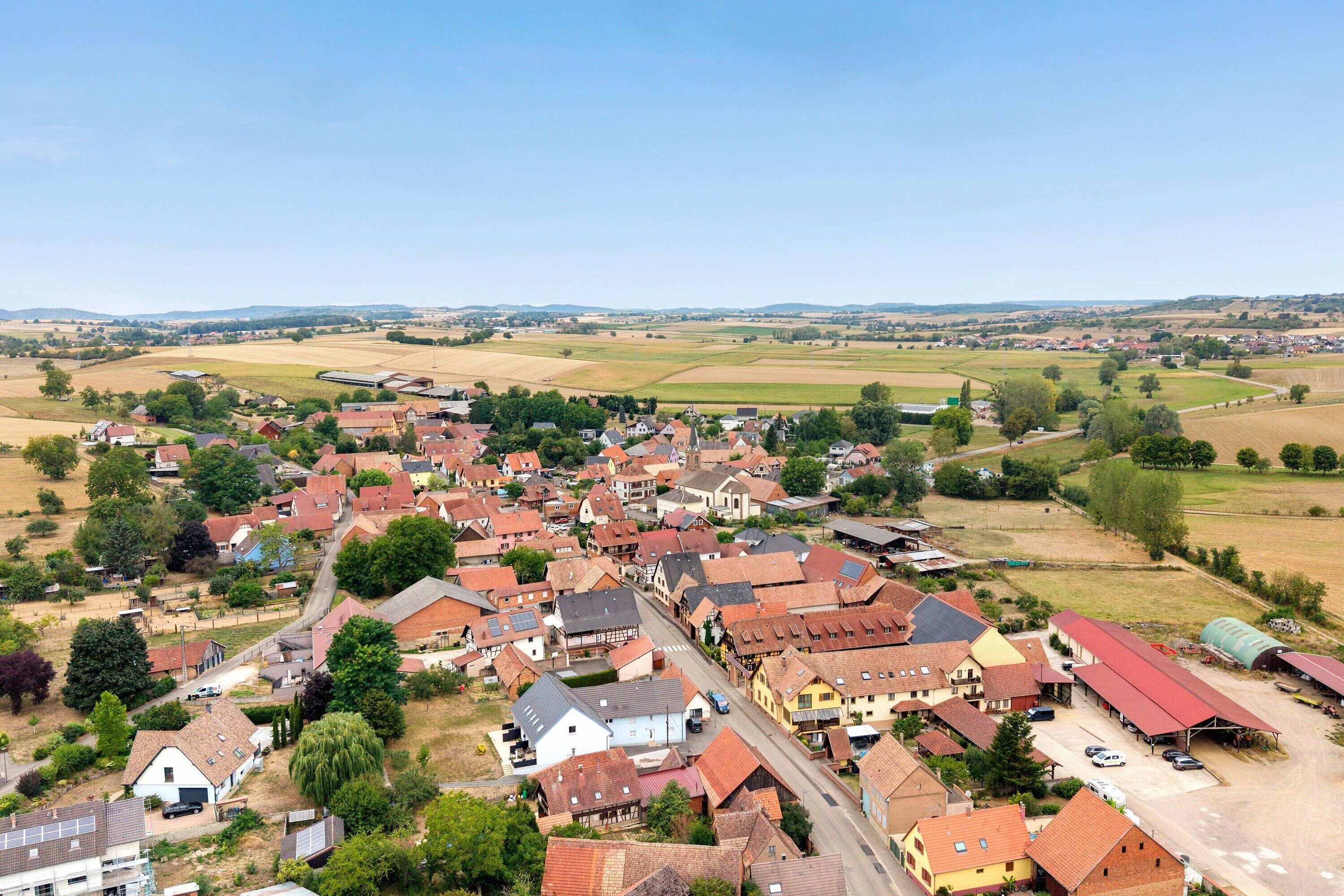 A rural village with traditional houses, a main road, and surrounding fields.