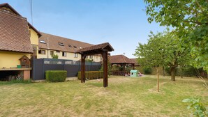 A residential area with a house, a covered outdoor seating area, and a small play structure.