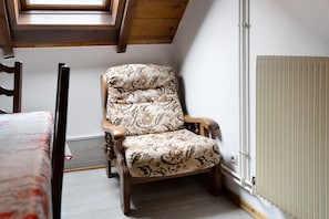 A wooden chair with floral upholstery in a room with a sloped ceiling and a radiator. - Winter Room – Breakfast Included, Games Room – Bossendorf (Bossendorf)