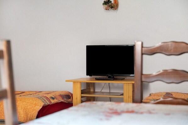 A bedroom with a bed, a wooden nightstand, and a television.
