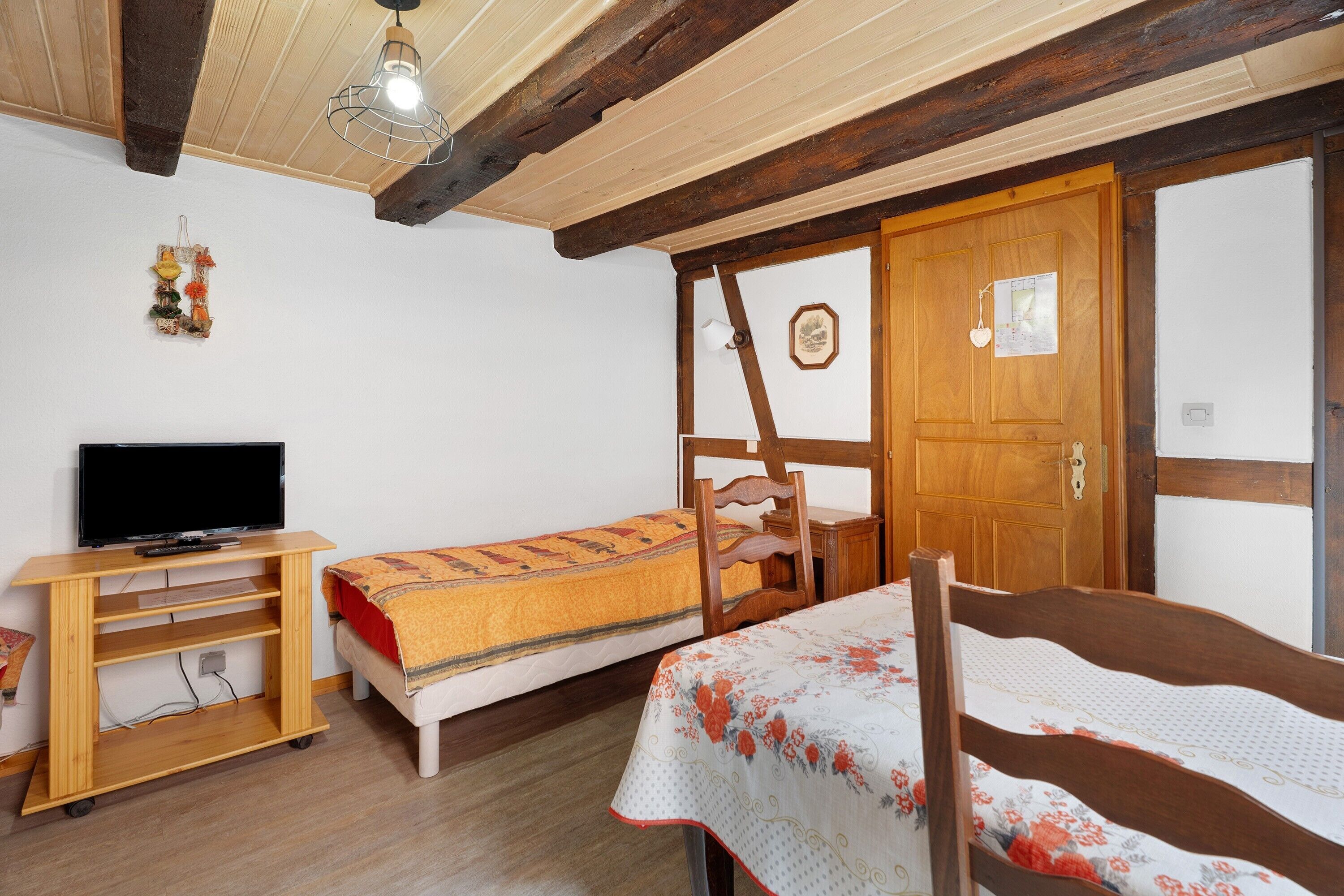Een kamer met een bed, bureau, televisie en kledingkast.