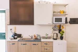 Eine kompakte Küchenzeile mit Mikrowelle, Wasserkocher und kleinem Kühlschrank.