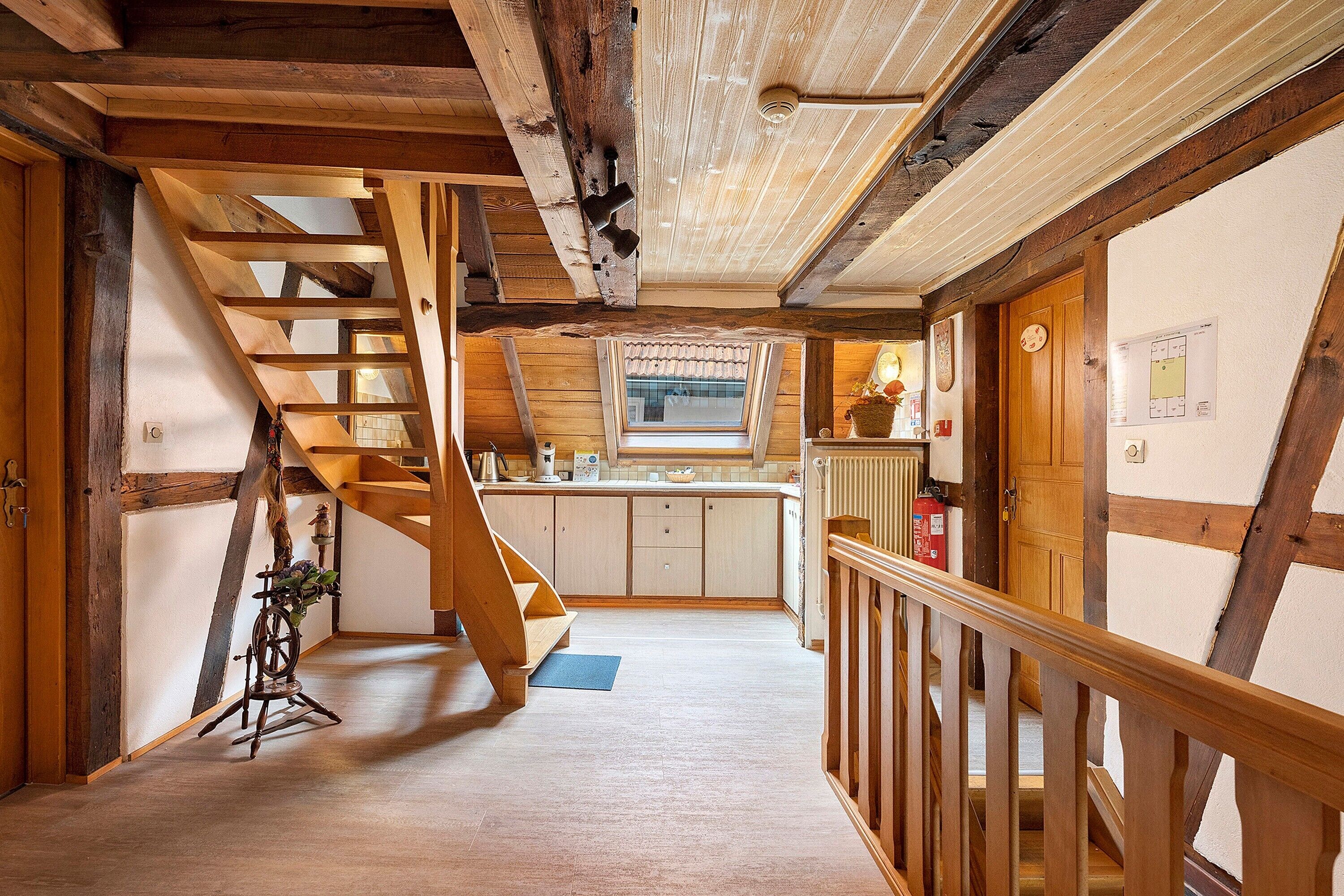 Un intérieur en bois avec un escalier, un coin cuisine et une fenêtre donnant sur un paysage agréable.