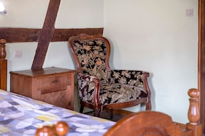A room with a wooden bed, a wooden dresser, and a floral upholstered chair.