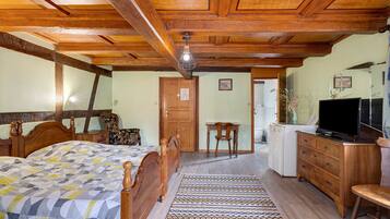 Une chambre avec un lit en bois, un bureau, une chaise, une télévision et un réfrigérateur.