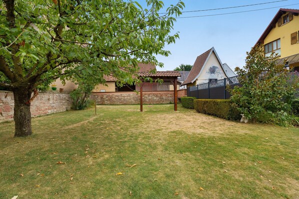 A residential area with a grassy lawn, a swing set, and a stone wall.