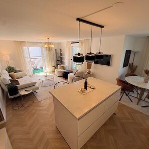 A modern living room with a sofa, coffee table, and a dining area with chairs. - Cozy Lakeside Apartment near Disneyland Paris (Serris)