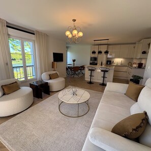 Un salon moderne comprenant un canapé, une table basse et un coin repas avec des chaises.