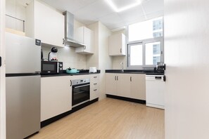 A modern kitchen with white cabinets, a black countertop, a microwave, a toaster, and a window providing natural light. - Vogue, Dec Tower Marina near Ain Dubai and JBR (Dubai Marina)