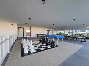 A spacious outdoor area with a large checkered floor, chess pieces, and tables, likely for outdoor dining or events. - Vogue, Al Furjan Pearlz by Danube near Ibn Battuta Mall (Al Furjan)