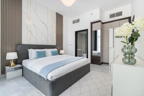 A modern bedroom with a large bed, bedside tables, a marble wall, and a glass vase with flowers. - Vogue, Al Furjan Pearlz by Danube near Ibn Battuta Mall (Al Furjan)