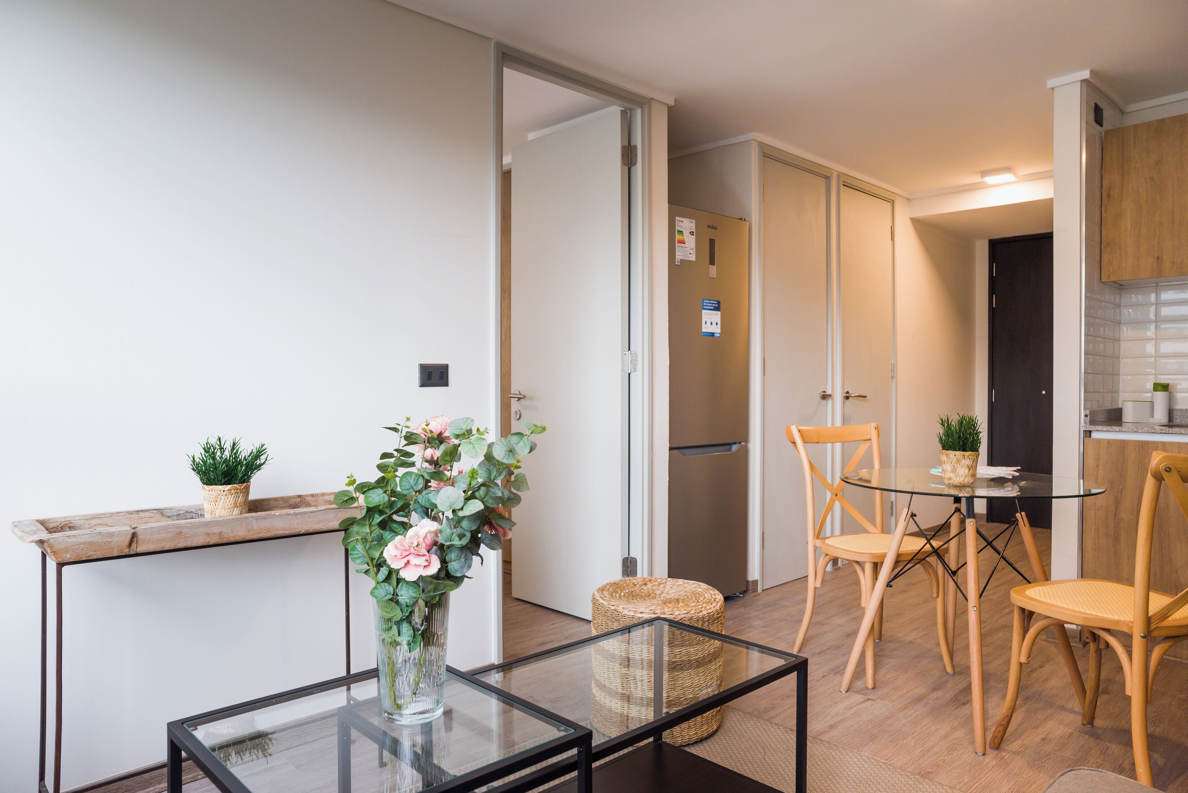 Een moderne keuken met een eethoek, een glazen tafel en een rieten mand.