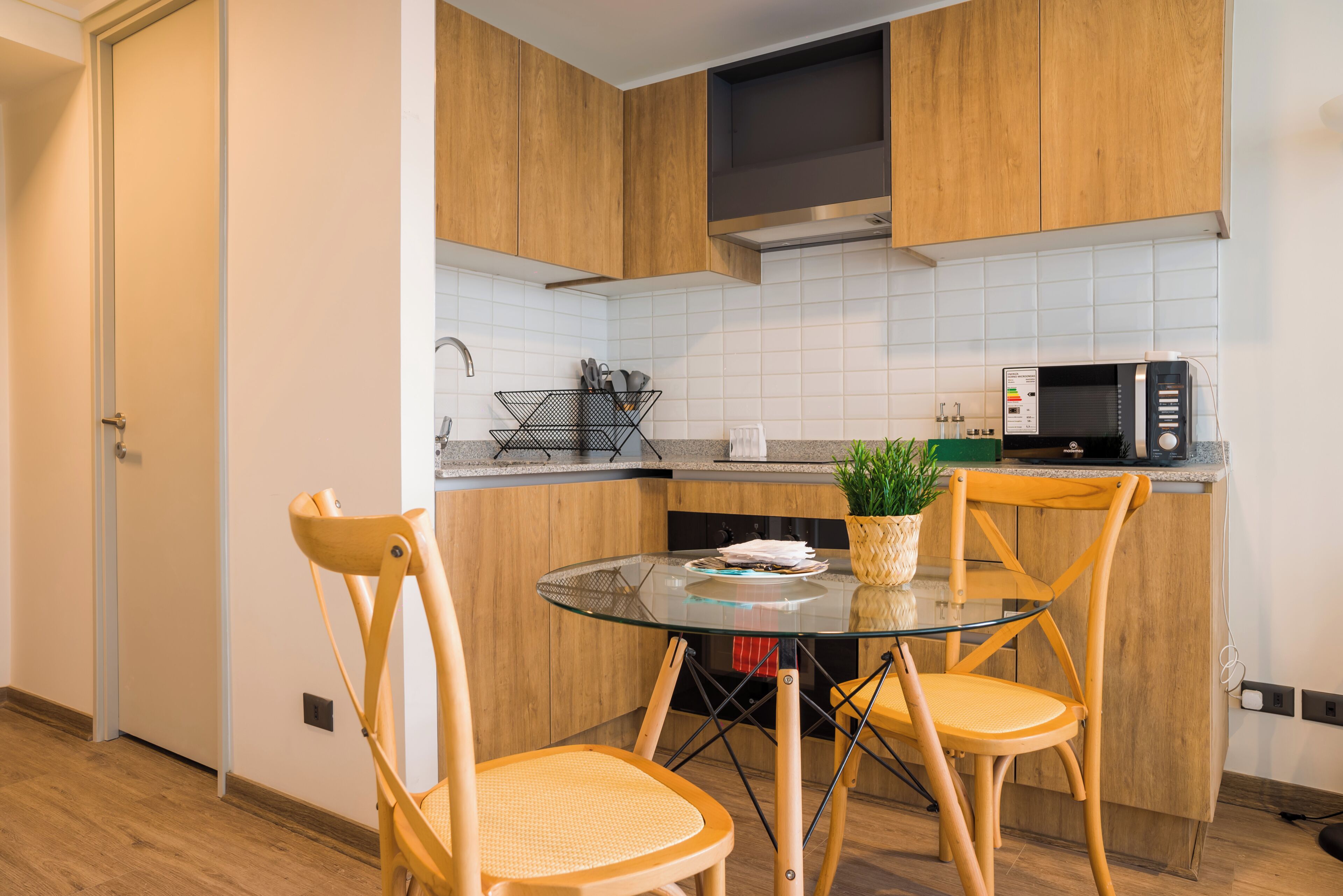 Una cocina moderna con armarios de madera, una mesa de vidrio y dos sillas.