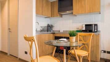 Una cocina moderna con armarios de madera, una mesa de vidrio y dos sillas.
