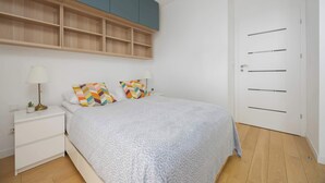 Een slaapkamer met een bed, nachtkastjes, een lamp, een deur en een inbouwkast.