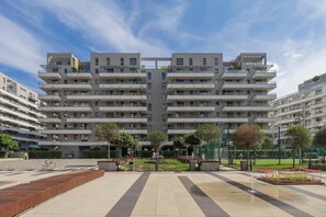 A multi-story residential building with balconies, a central courtyard, and a playground area. - Klimatisiertes Apartment | Parkplatz | Warschau-Wola (Warszawa)