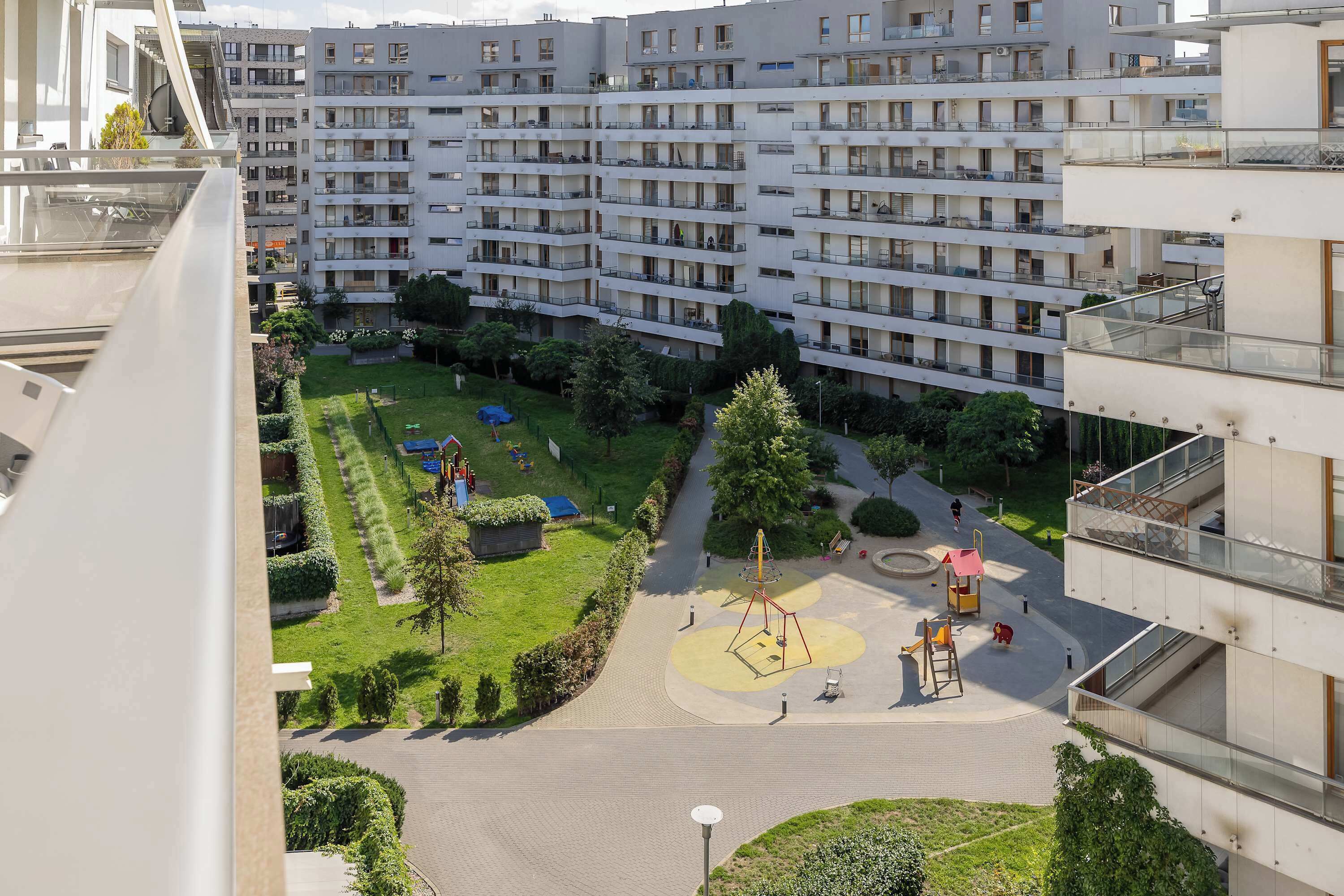 Un edificio residencial con varios balcones, un parque infantil y un jardín bien cuidado.