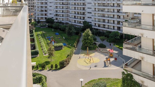 Een woongebouw met meerdere balkons, een speeltuin en een verzorgde tuin.