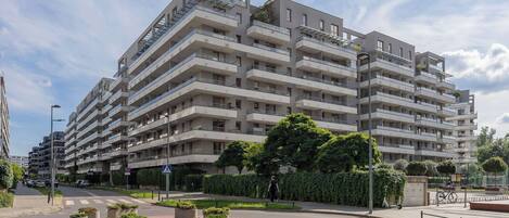 Un edificio residencial de varios pisos con balcones, un paso de peatones y una glorieta.