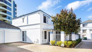 Un immeuble résidentiel à l’extérieur blanc, doté d’un garage et d’une allée pavée.