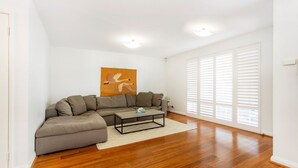 Un salon avec un canapé d’angle, une table basse et un tableau accroché au mur.