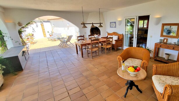 Een ruime woonkamer met een eettafel, rieten meubels en uitzicht op het terras.