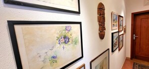 A hallway with framed artwork on the walls, a wooden door, and a textured wall.