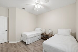 A bedroom with two single beds, a ceiling fan, a bedside table with a lamp, and a door. - Lux Mins 2 Crescent Beach/Flagler Hospital/Ampitheatre (St. Augustine)