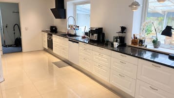 Een moderne keuken met witte kasten, een zwart aanrechtblad en een raam dat voor natuurlijk licht zorgt.