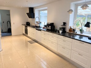 A modern kitchen with white cabinetry, a black countertop, and a window providing natural light. - Farmhouse in Bælum - rural tranquility 20 minutes from Aalborg (Bælum)