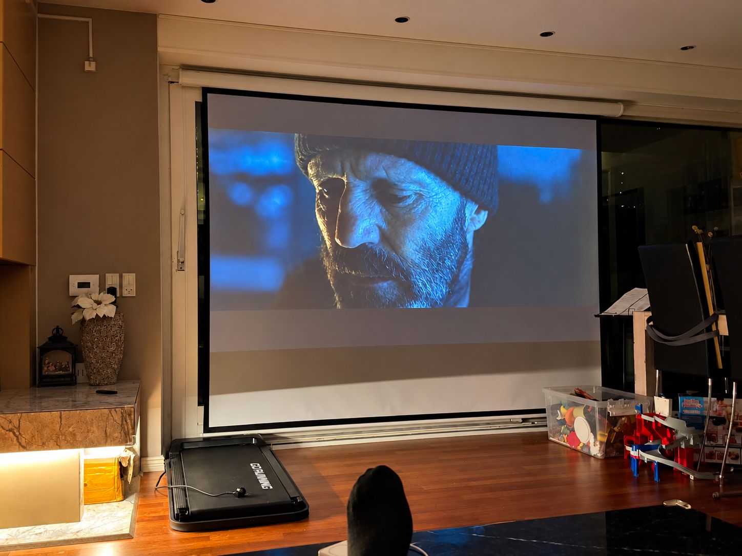 Ein Heimkino mit großem Bildschirm, einem Laufband und einem Notenständer.