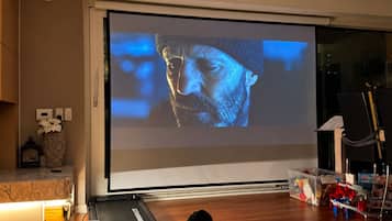 Ein Heimkino mit großem Bildschirm, einem Laufband und einem Notenständer.