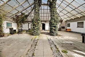 A greenhouse with a glass roof, stone walls, and a central pathway. - Farmhouse in Bælum - rural tranquility 20 minutes from Aalborg (Bælum)
